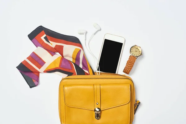 Vista superior del bolso, smartphone, reloj, bufanda y auriculares sobre fondo blanco - foto de stock