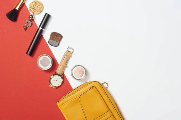 Acostado plano con rímel, reloj, bolso, sombra de ojos, cepillos cosméticos y pendientes - foto de stock