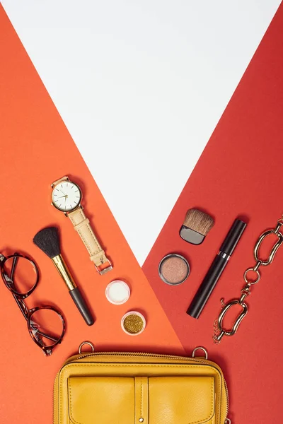 Flachlage mit Wimperntusche, Uhr, Gelber Sack, Armband, Lidschatten, Rouge, Brille und Kosmetikbürsten — Stockfoto