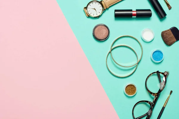 Vista superior de rímel, relógio, batom, pulseiras, sombra, blush, óculos e escovas cosméticas — Fotografia de Stock