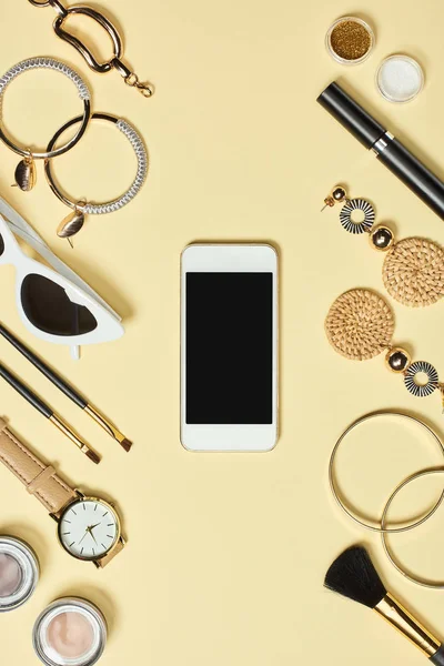 Top view of watch, bracelets, earrings, sunglasses, eyeshadow, blush, cosmetic brushes, mascara and smartphone with copy space — Stock Photo