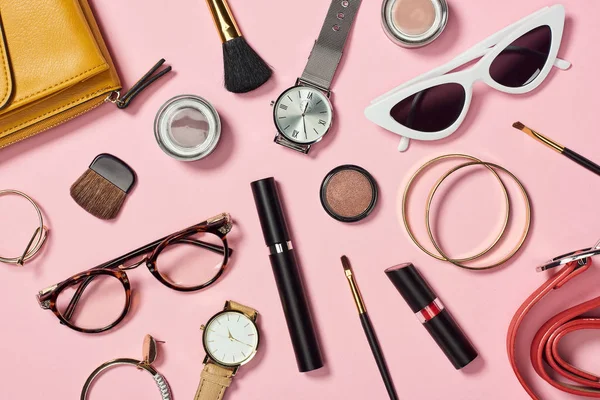 Top view of watches, lipstick, earrings, glasses, sunglasses, bag, eyeshadow, blush, belt, cosmetic brushes, bracelets and mascara — Stock Photo