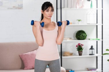 evde dumbell ile egzersiz yaparak sportif genç kadın