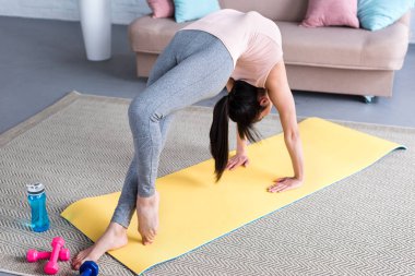 güzel genç kadın evde bir bacaklı tekerlek yoga poz (Eka Pada Urdhva Dhanurasana) için hazırlanıyor