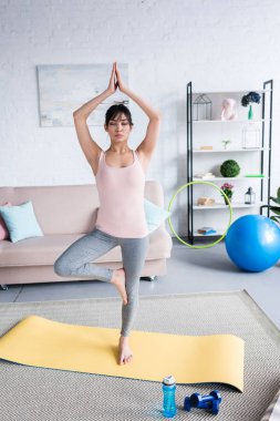 çekici genç kadın evde pratik yoga ağaç poz (Vrksasana)