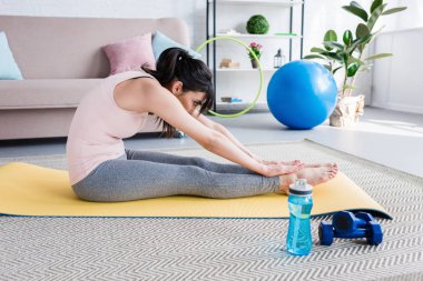 atletik genç kadının ileri bend yoga mat evde yapması