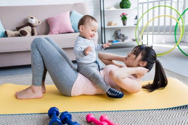 Genç güzel annem evde küçük çocuğuyla birlikte yoga mat çalışma dışarı