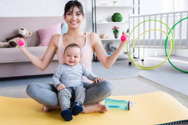 yoga mat üzerinde oturan ve evde egzersizleri yapıyor mutlu çocuk ile genç sportif anne