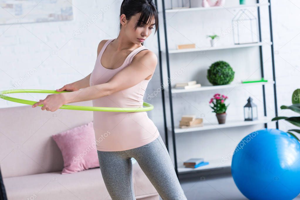 fit young woman working out with hula hoop at home