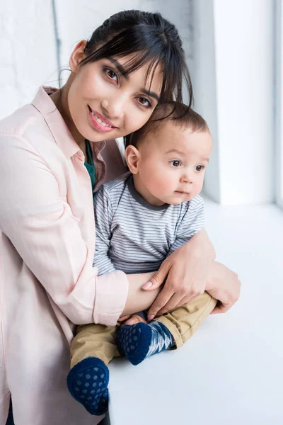 Joven Sonriente Madre Abrazando Pequeño Hijo Mirando Cámara — Foto de stock gratuita