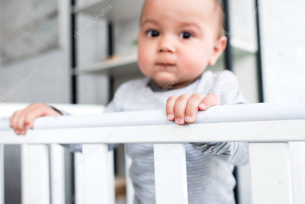 close-up portrait of adorable little child in baby cot looking at camera