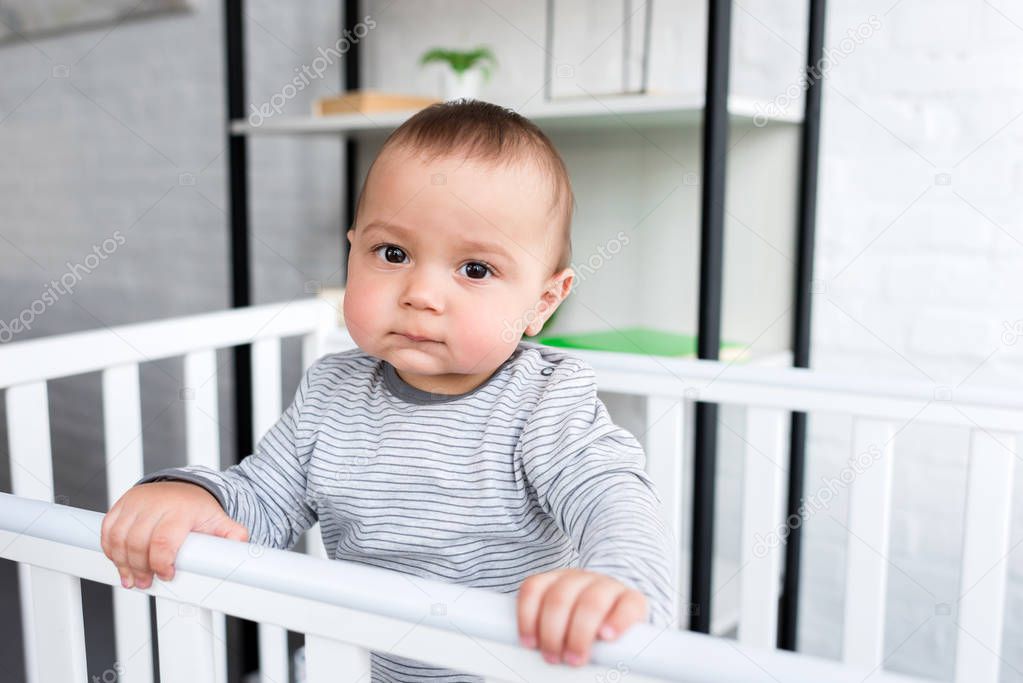 close-up portrait of cute little child in baby cot looking at camera