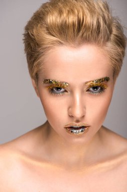 Altın glitter gri izole kamera bakarak yüzünde güzel bir kadınla