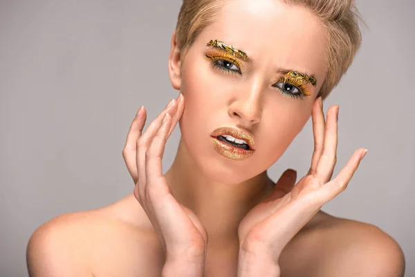 魅力的なグレーに分離カメラ目線の顔に黄金の輝きを持つ女性のイライラ — ストック写真