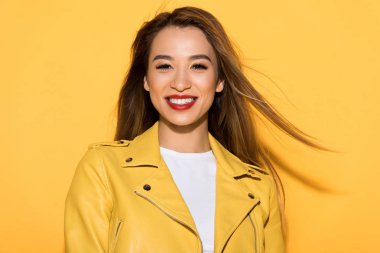 smiling asian female model posing on yellow background  clipart
