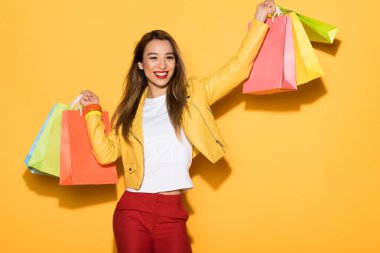 Asyalı kadın ile alışveriş torbaları sarı arka plan üzerinde gülümseyen 