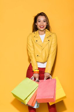 mutlu kadın Alışverişkoliğin sarı zemin üzerine kağıt torbalar ile ayakta 