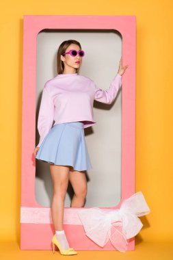 şık Asyalı kadın modeli güneş gözlüğü ve sarı zemin üzerine yay ile dekoratif kutu
