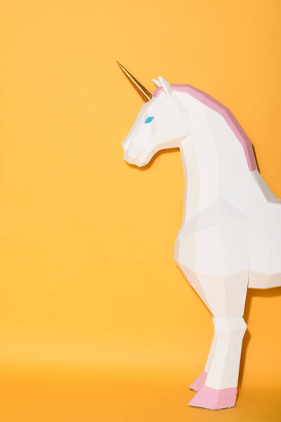 partial view of decorative unicorn standing on yellow background 