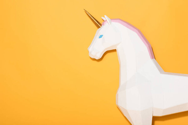 side view of decorative unicorn standing on yellow background 