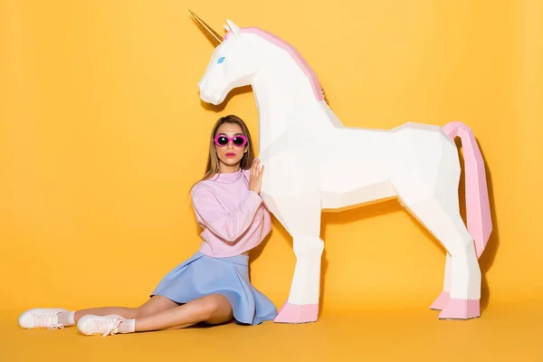Modelo Femenina Joven Gafas Sol Sentado Suelo Abrazando Unicornio Decorativo —  Fotos de Stock