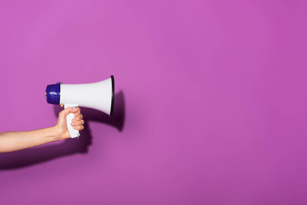 cropped image of woman holding megaphone on purple background 