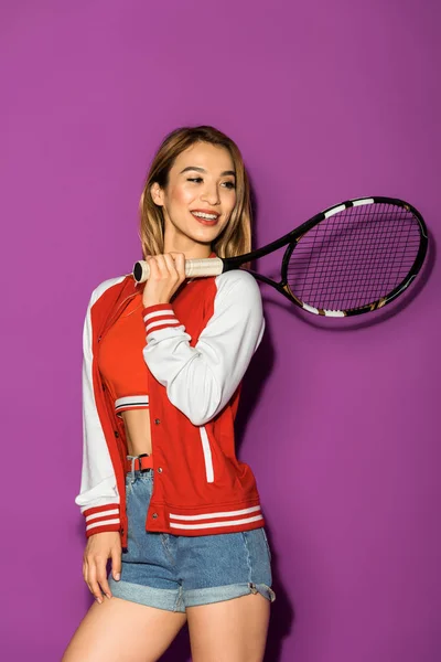美丽微笑的亚洲女孩拿着网球拍 看着远离紫色的孤立 — 图库照片