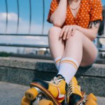 Обрезанный снимок стильной девушки в винтажных роликовых коньках, сидящих на улице