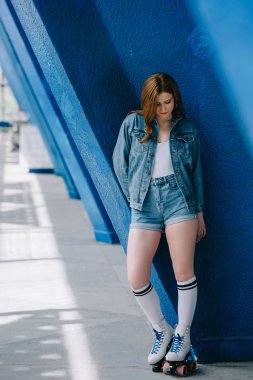 denim giysiler, yüksek çorap ve retro mavi duvara yaslanmış paten şık kadın