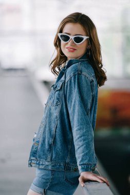 retro güneş gözlüğü ve şık denim giyim gülümseyen kadın yan görünüm
