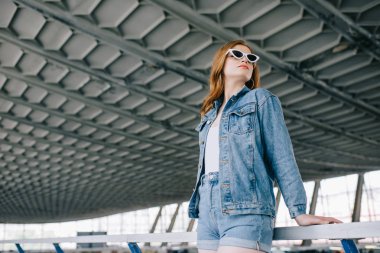 denim giyim ve retro güneş gözlüğü genç moda kadın düşük açılı görünüş