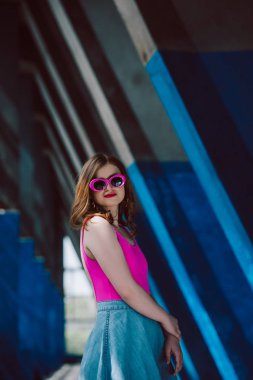 pembe retro güneş gözlüğü ve kot etek şık gülümseyen kadın portresi