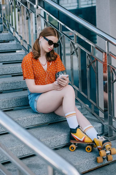 Stylish Girl Sunglasses Roller Skates Sitting Stairs Listening Music Smartphone — Free Stock Photo