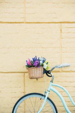 close-up view of bicycle with beautiful colorful flowers in basket near wall  clipart