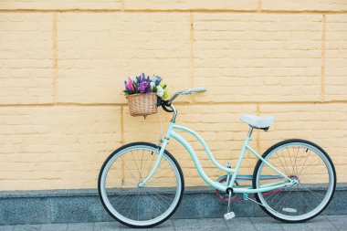 white bicycle with beautiful colorful flowers in basket near wall  clipart
