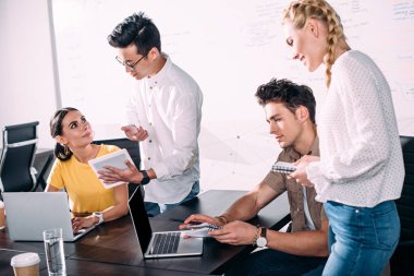 Grup Toplantısı dizüstü bilgisayarlar ve dijital tablet ile modern ofiste çok ırklı iş arkadaşları 