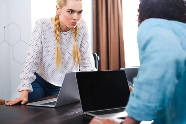 Jovem Empresária Irritada Olhando Para Colega Masculino Mesa Com Laptops — Fotografia de Stock