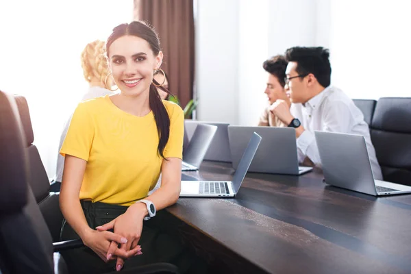 Lachende Jonge Zakenvrouw Kijken Camera Terwijl Haar Partners Met Discussie — Stockfoto