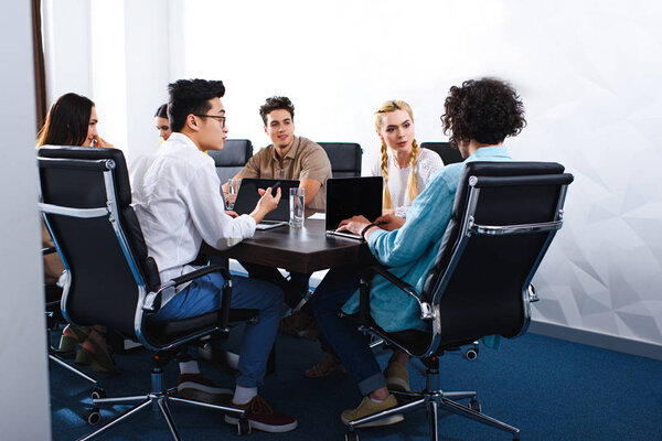 мультиэтнические бизнесмены за столом с ноутбуками в современном офисе
 