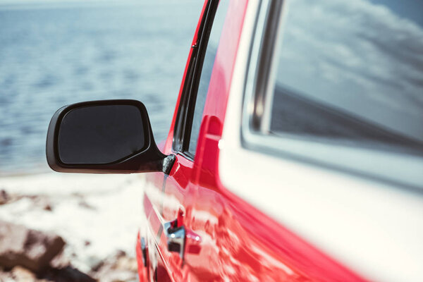 селективный фокус зеркала автомобиля, красный джип у моря
