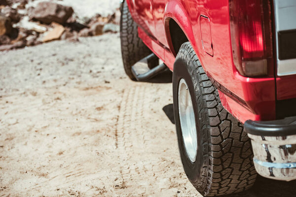 колеса красного автомобиля на песчаной дороге во время поездки
