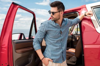 kırmızı arabanın yakınında duran yakışıklı şık gezgin