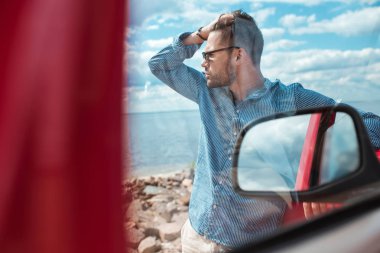 seçici odak araba deniz kenarında ayakta yakışıklı erkek gezgin