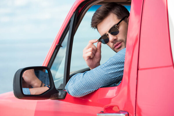 handsome male driver in sunglasses sitting in car