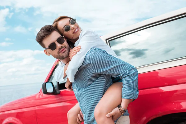 Happy Young Couple Travelers Piggybacking Red Car — Stock Photo, Image