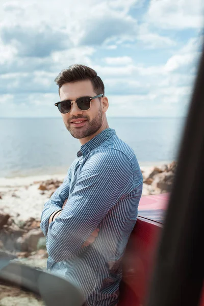Knappe Glimlachende Man Die Auto Buurt Van Zee Tijdens Reis — Gratis stockfoto