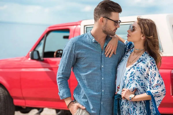 Stilvolles Junges Paar Mit Sonnenbrille Umarmt Sich Neben Rotem Auto — kostenloses Stockfoto