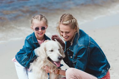 gülümseyen aile ile golden retriever köpek deniz kıyısında