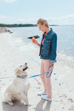 deniz kıyısında golden retriever köpek topla oynamayı kadın