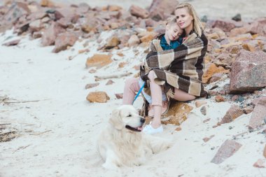 güzel anne ve köpek ile kıyıda oturan battaniye içinde uyuyan çocuk 